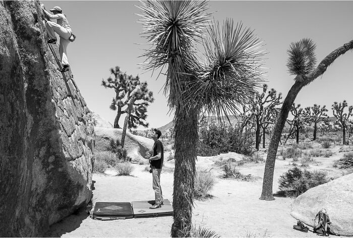 Black and white photograph capturing the hidden poetry of everyday life with rock climbing in a desert landscape.