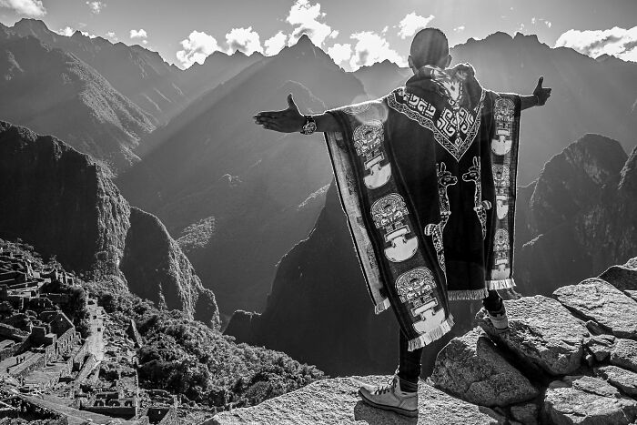 Black and white photograph capturing the hidden poetry of everyday life with a person overlooking mountainous landscape.