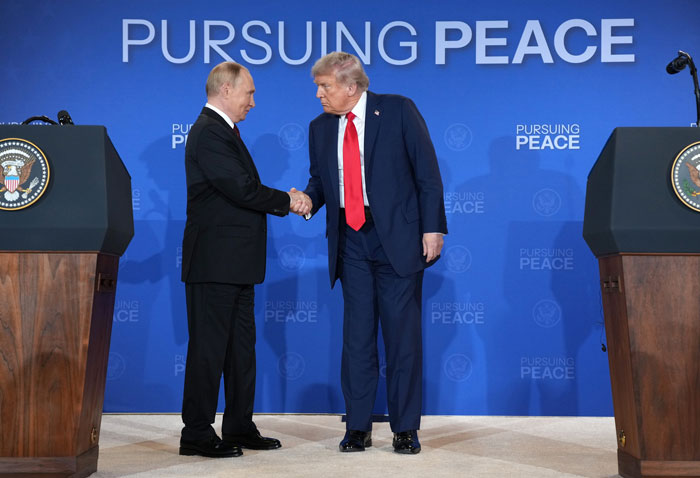 Vladimir Putin shaking hands with Donald Trump at Alaska meeting amid leg twitching and exoskeleton rumors.