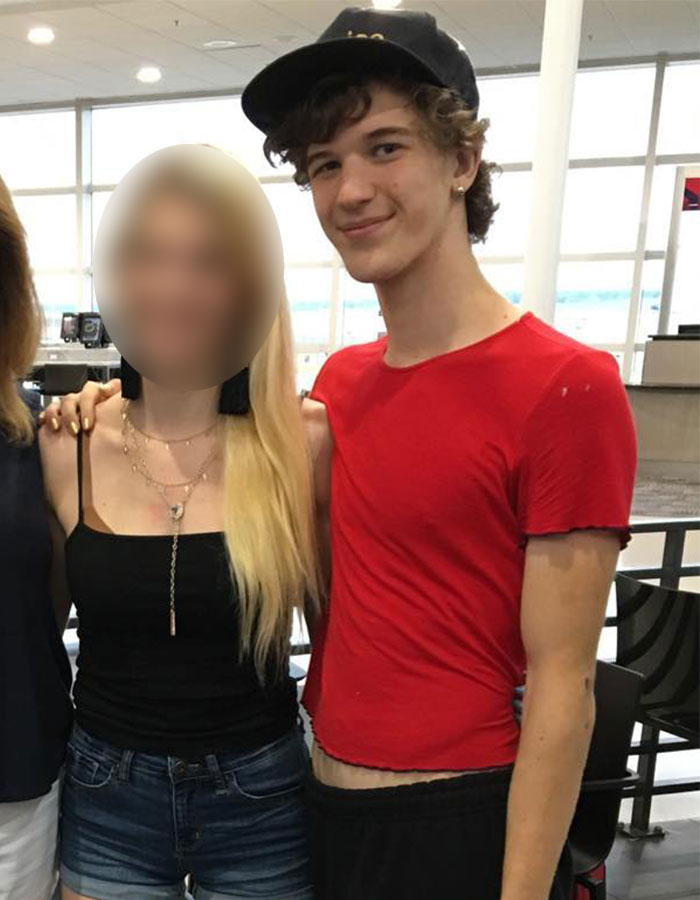Young man in a red shirt and black cap standing next to a woman with long blonde hair, in a bright indoor setting. Young man in a red shirt and black cap standing next to a woman with long blonde hair, in a bright indoor setting.
