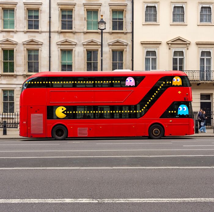 Red double-decker bus creatively reimagined with famous Pac-Man characters and iconic pixelated game elements.