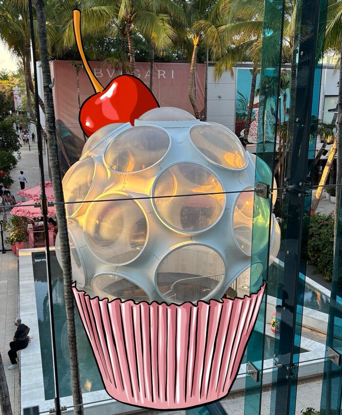 Giant cupcake with a cherry reimagined by artist blending famous characters and everyday objects in a creative landscape.