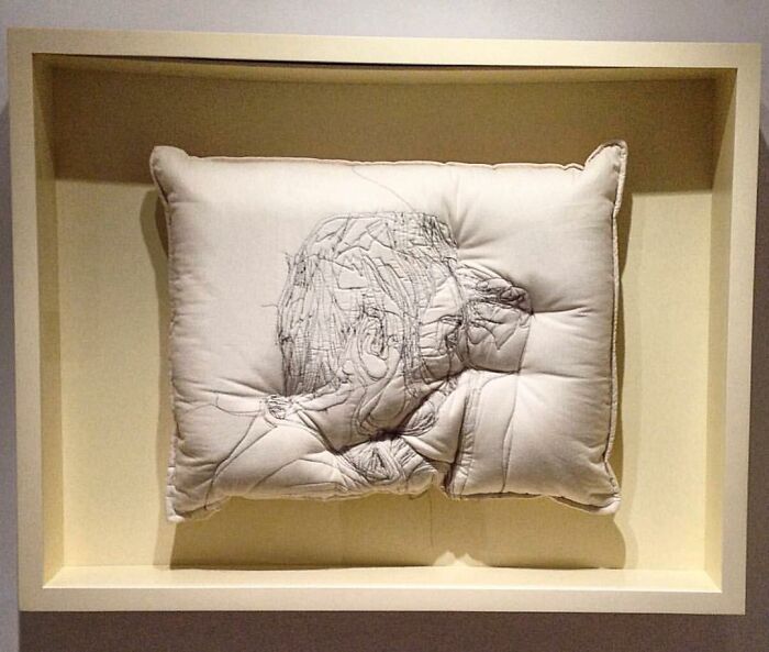 Embroidered pillow by Maryam Ashkanian featuring a detailed thread portrait capturing the beauty of sleep in a shadow box frame.