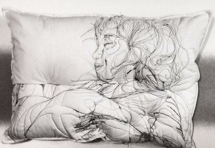 Embroidered pillow featuring a detailed, dreamy stitched line art of a person resting peacefully.