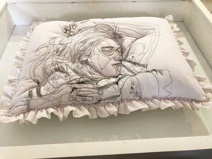 Embroidered pillow by Maryam Ashkanian with detailed thread art depicting two figures in an intimate embrace.