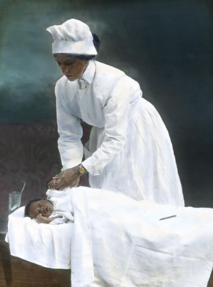 African American nurse caring for a sleeping infant in a colorized photo depicting 1920s African American reality.