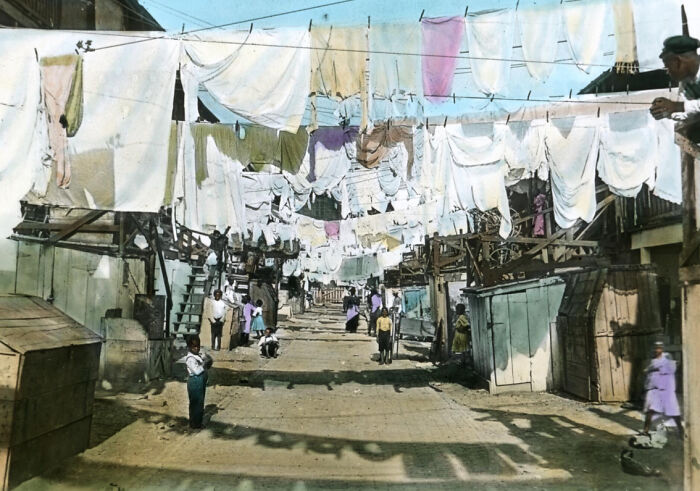 Colorized photo showing African American street life and laundry hanging in the 1920s reflecting African American reality.