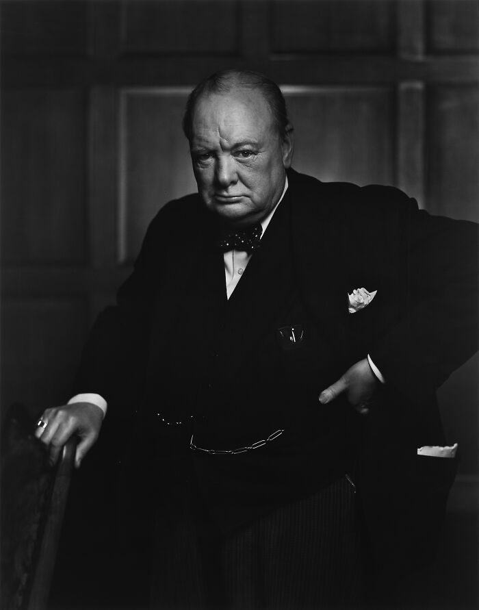 Black and white portrait of a serious man in a suit, representing triumph and tragedy of the 20th century.