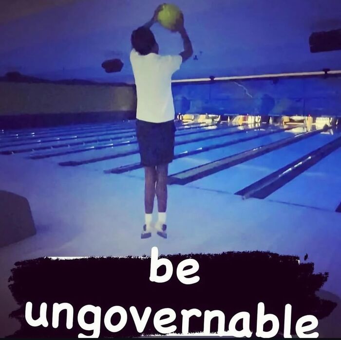 Person holding a yellow ball above their head in a bowling alley, featuring cursed images from a popular IG page.