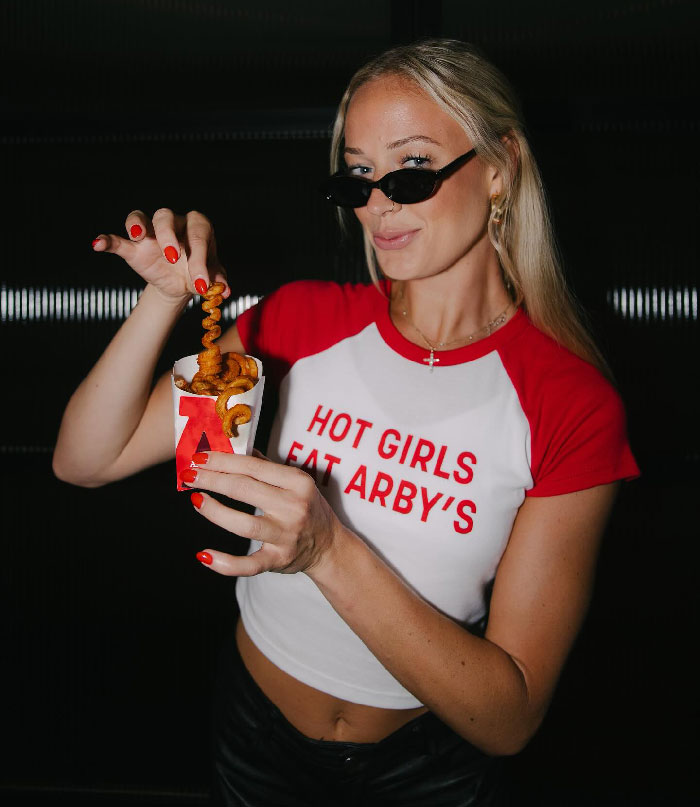 Woman wearing sunglasses and a red and white shirt holding curly fries, unrelated to viral footage of flying dildo hitting WNBA star. Woman wearing sunglasses and a red and white shirt holding curly fries, unrelated to viral footage of flying dildo hitting WNBA star.