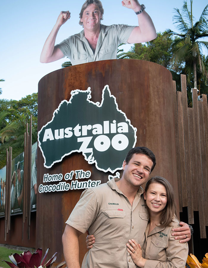 Steve Irwin’s children Robert and Bindi smiling in front of Australia Zoo sign with Steve’s image above. - 7