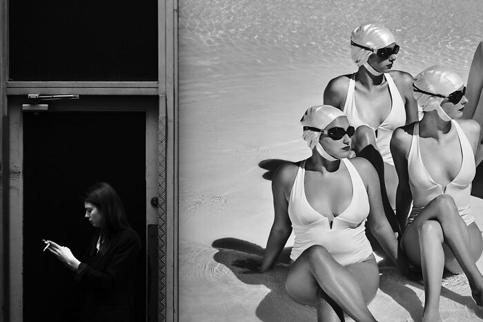Black and white powerful street photo showing a woman smoking next to a vintage poster of three swimmers in swimsuits and caps.
