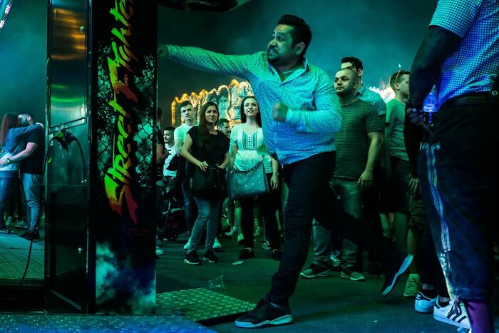 Man throwing a dart in a vibrant urban setting with a crowd watching, capturing powerful street photos of everyday life.