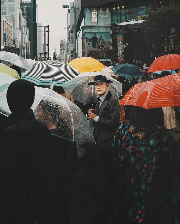 Crowded street scene in rain with people holding colorful umbrellas, capturing powerful street photos of everyday life moments.