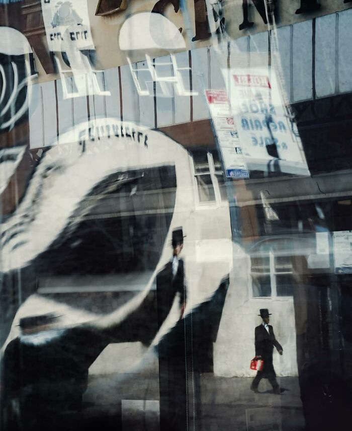 Abstract street photo showing a man in a hat reflected in windows, capturing the beauty of everyday life in urban scenes.