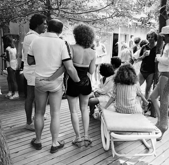Group of people socializing outdoors on a wooden deck, captured in a powerful street photo revealing everyday life beauty.