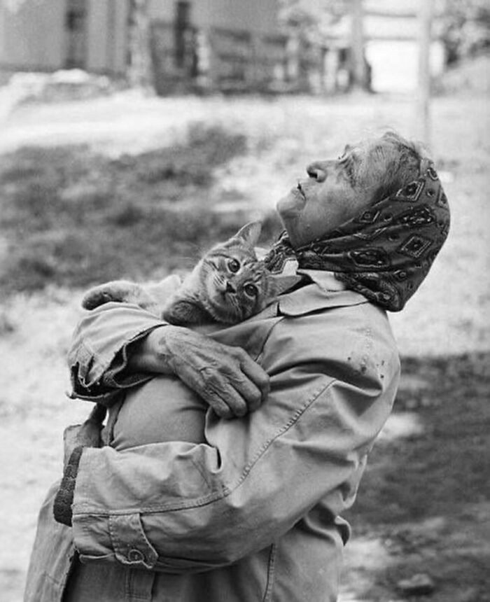 Elderly woman holding a cat close, captured in a powerful street photo revealing the beauty of everyday life.
