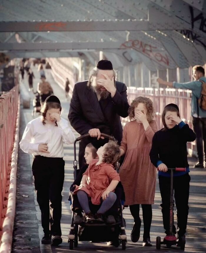 Orthodox Jewish family walking on a bridge, captured in a powerful street photo revealing the beauty of everyday life.