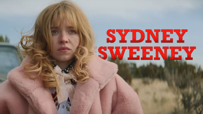 Sydney Sweeney in a pink coat outdoors with her name in red text, relating to movie flop and American Eagle backlash.