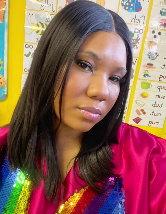 Teacher posing in colorful outfit in classroom with educational posters, related to teacher's private parts song viral topic. Teacher posing in colorful outfit in classroom with educational posters, related to teacher's private parts song viral topic.