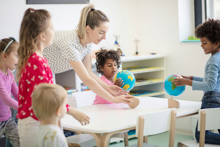 Teacher engaging first grade kids with educational globes during a fun and interactive classroom activity. Teacher engaging first grade kids with educational globes during a fun and interactive classroom activity.