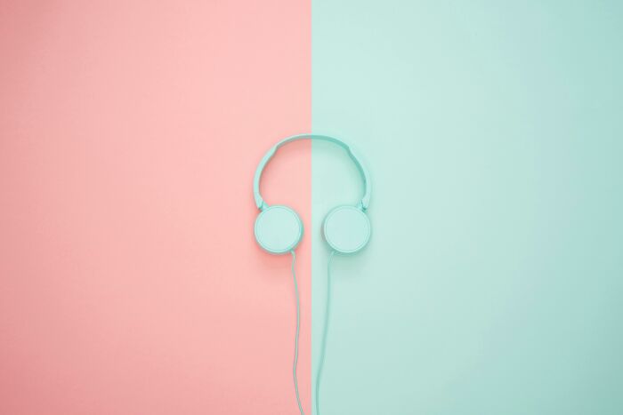 Headphones placed at the center of a pink and blue background representing then vs now scenarios concept.