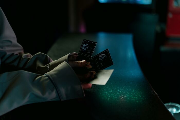 Person holding cinema tickets in a dimly lit setting, illustrating then vs now scenarios comparison.