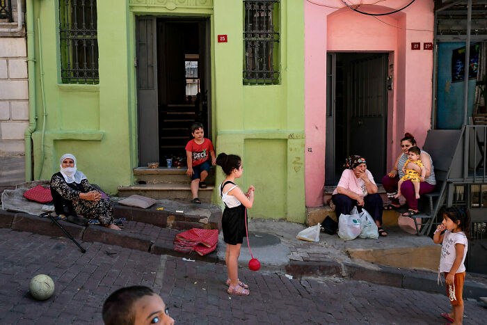 Neighborhood scene with children and adults in front of colorful buildings, capturing unforgettable street photos of everyday life.