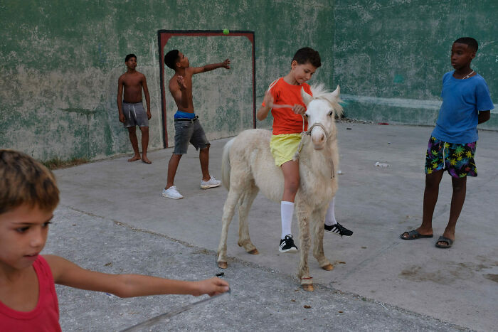 Children playing and a boy riding a white pony in a street scene captured in unforgettable street photos.