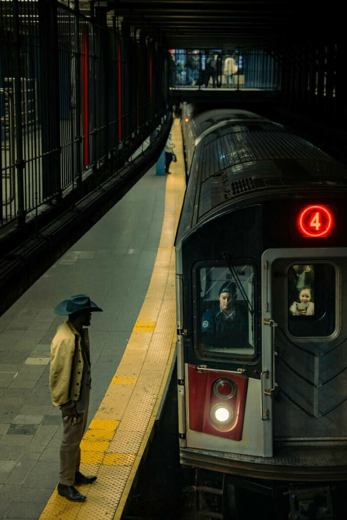 Man in a hat standing on subway platform as train arrives, captured in unforgettable street photos turning life into art.