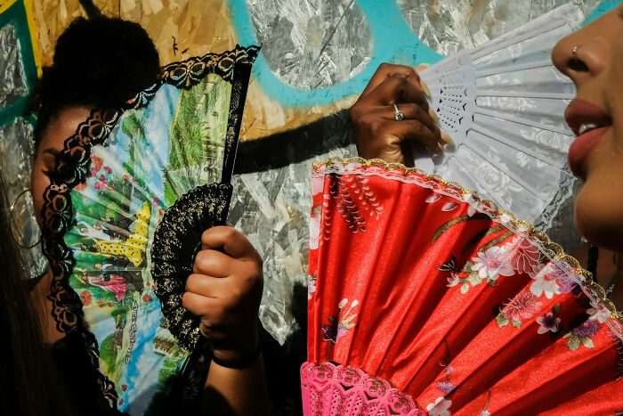 Two people holding colorful hand fans, capturing a vibrant moment in unforgettable street photos of everyday life.