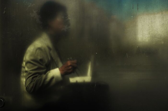 Blurry street photo of a person using a laptop, capturing everyday life through unforgettable street photography art.