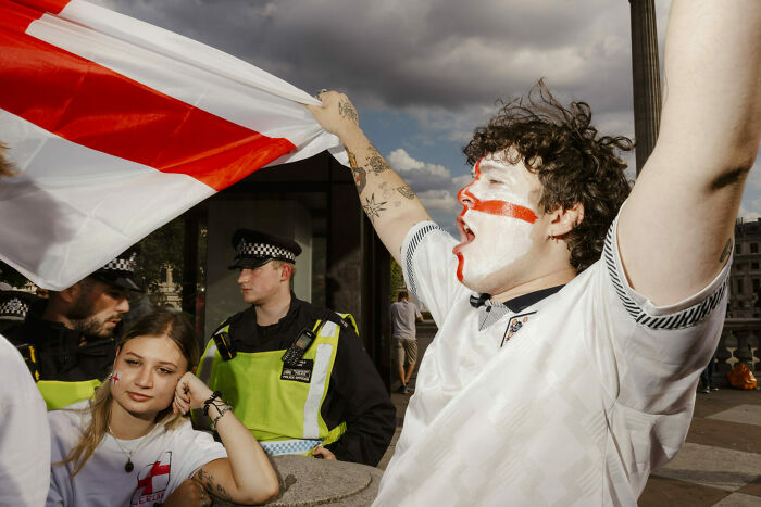 Street photo of passionate fans with face paint and a flag, capturing unforgettable moments of everyday life as art.