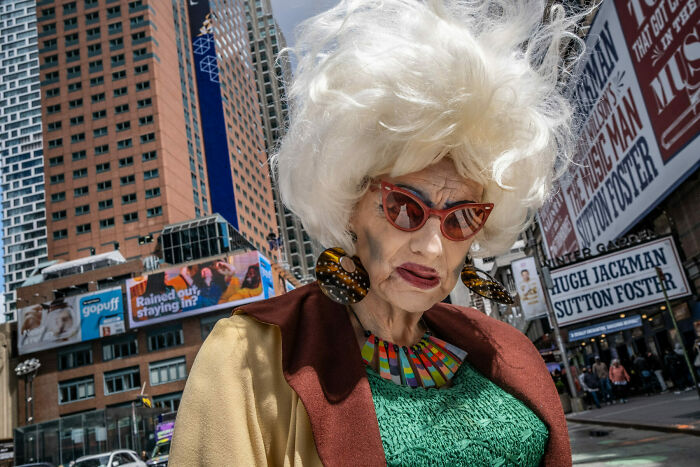 Eccentric person with white hair and bold accessories captured in a vibrant street photo showcasing everyday life as art.