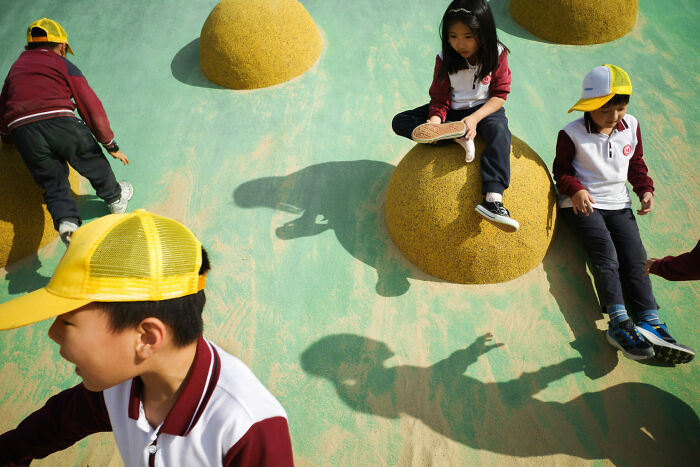 Children playing on yellow dome structures, captured in a vibrant street photo that turns everyday life into art.