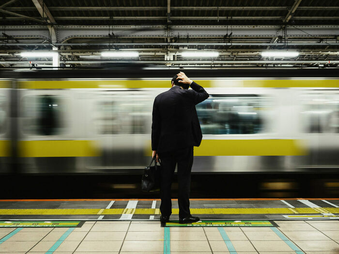 Man in a suit waiting at a busy subway platform, captured in a vibrant street photo turning everyday life into art.