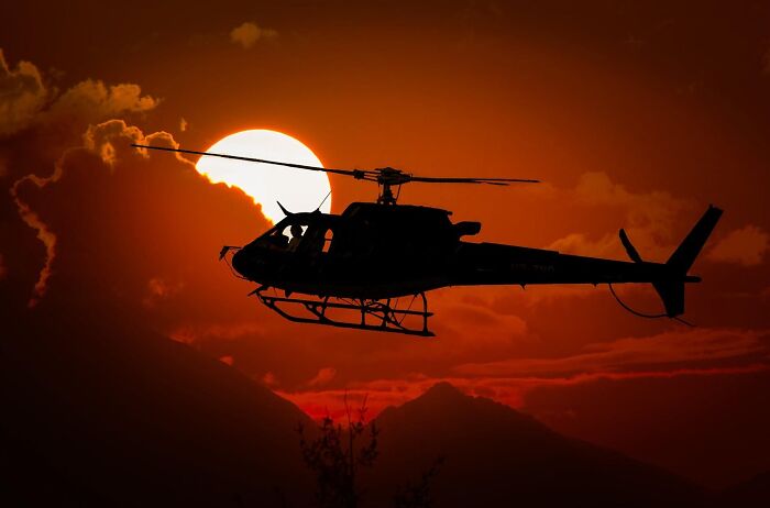 Helicopter flying at sunset with dramatic sky and mountains, a stunning photo capturing nature and life around the world.