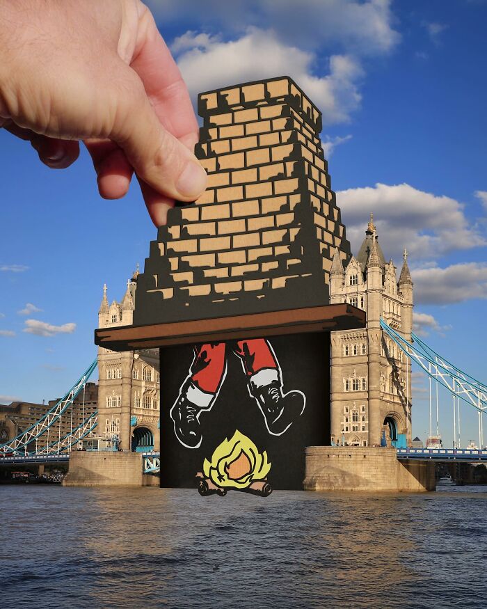 Hand holding paper cutout of Santa climbing chimney over London Tower Bridge creating a surprising travel art scene.