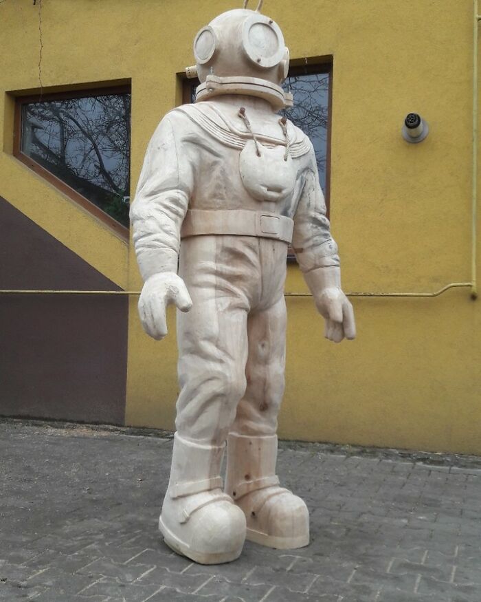Wooden sculpture of a vintage deep-sea diver created by a chainsaw artist from a forgotten tree trunk.