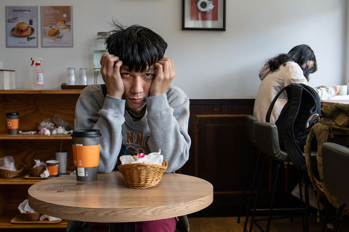 Young man sitting at a cafe table with coffee and food, capturing everyday moments during cultural travels worldwide.