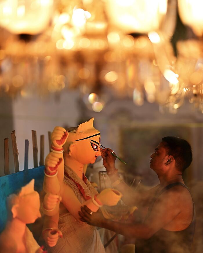 Artist carefully painting vibrant clay idol of Hindu goddess in a colorful India scene filled with life and tradition.