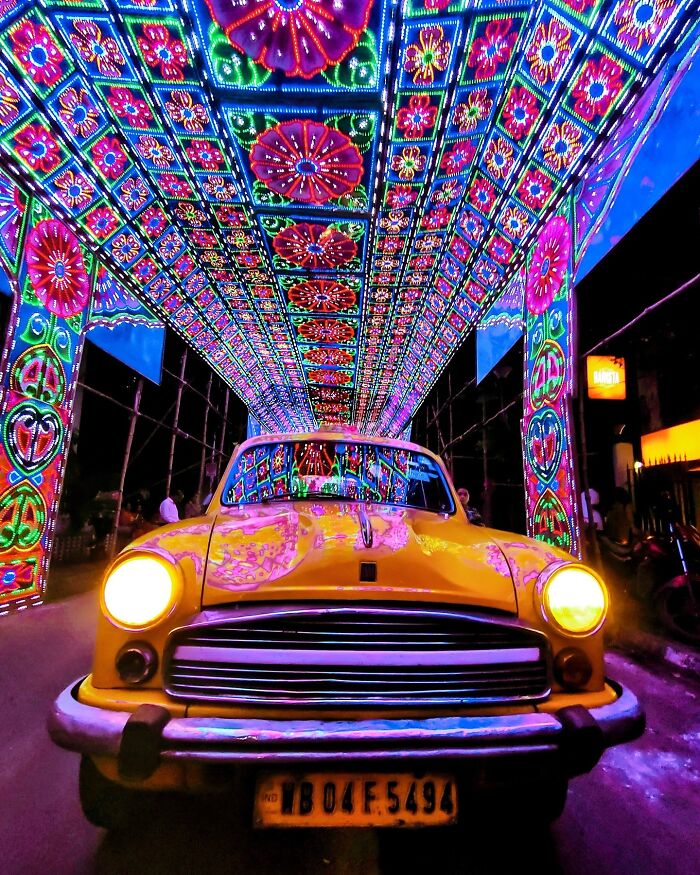 Yellow taxi under vibrant colorful lights installation in India, showcasing vivid photos that burst with color and life.