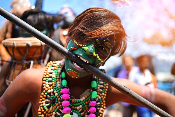 Young person with vibrant face paint and colorful beads, celebrating a lively festival in India bursting with color and life