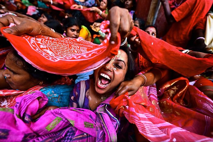Joyful woman surrounded by colorful scarves during a vibrant cultural celebration in India bursting with color and life
