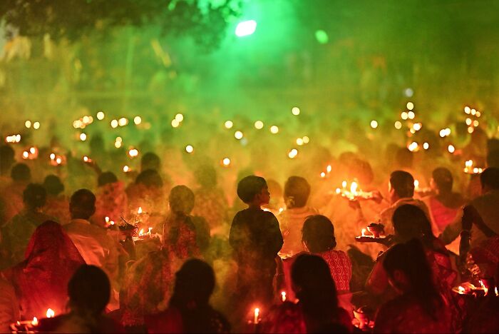 Crowd gathered holding lit lamps during a vibrant and colorful Indian festival, showcasing vivid photos of India life.