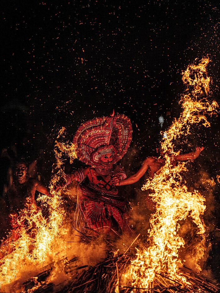 Traditional Indian fire dance with performers in vibrant red costumes surrounded by flames, showcasing vivid colors and life.