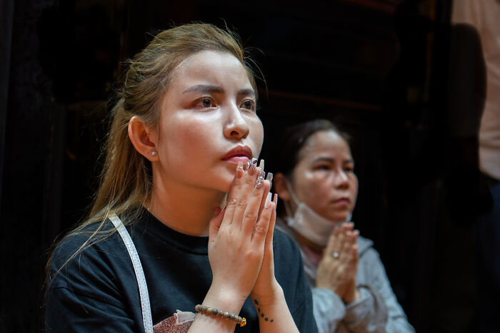 Two women with hands clasped in prayer, capturing cultural beauty during photographer’s travel across 50 countries.
