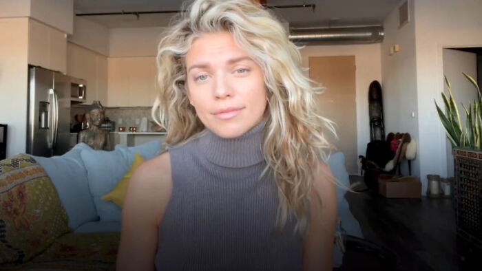 Blonde woman in a sleeveless gray turtleneck sitting in a living room, illustrating celebs trying to be relatable but out-of-touch.