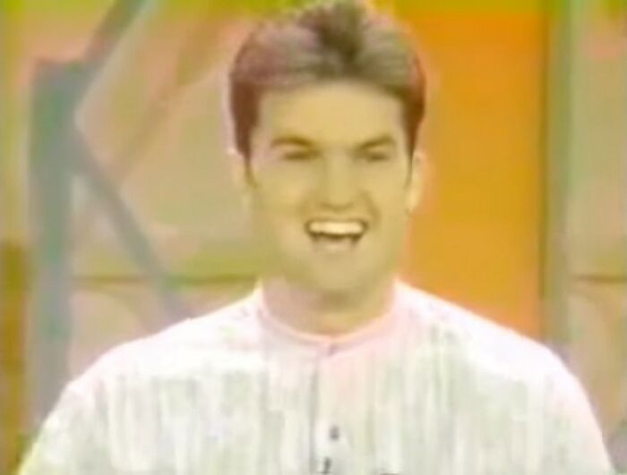 Smiling man in a vintage video frame with vibrant orange background, part of videos that gain meaning with context. - 3