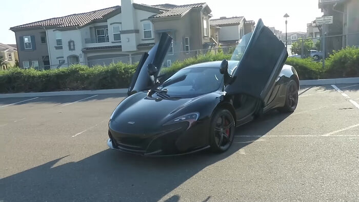 Black luxury sports car with doors open in a parking lot, featured in videos that reveal surprising context. - 17